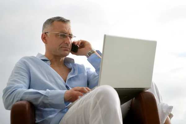 Man met een laptop en de telefoon in de buitenlucht — Stockfoto
