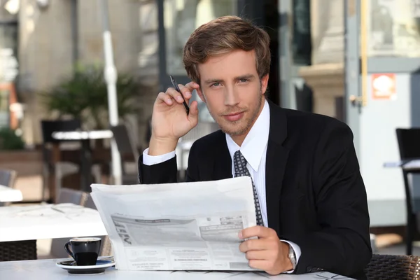 Young executive reading a newspaper in a cafe — Stock Photo, Image