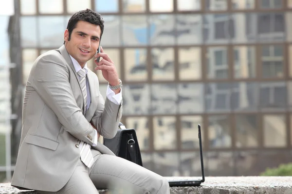 Businessman talking on phone in front of a laptop computer — Stock Photo, Image
