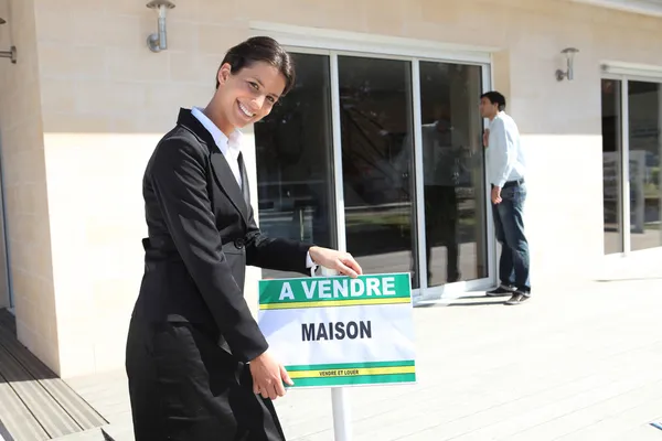 Estate agent with a French for sale sign — Stock Photo, Image