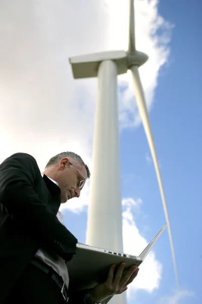 Zakenman controleren zijn laptop onder een windturbine — Stockfoto