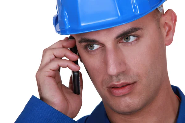 Man met een veiligheidshelm en mobiele telefoon — Stockfoto