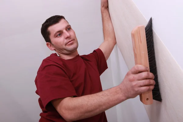 Baixo tiro de um homem alisamento papel de parede com uma grande escova — Fotografia de Stock
