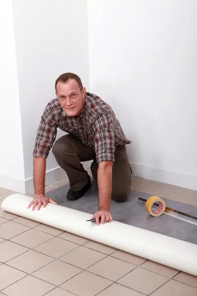 Homem que estabelece piso de pvc — Fotografia de Stock