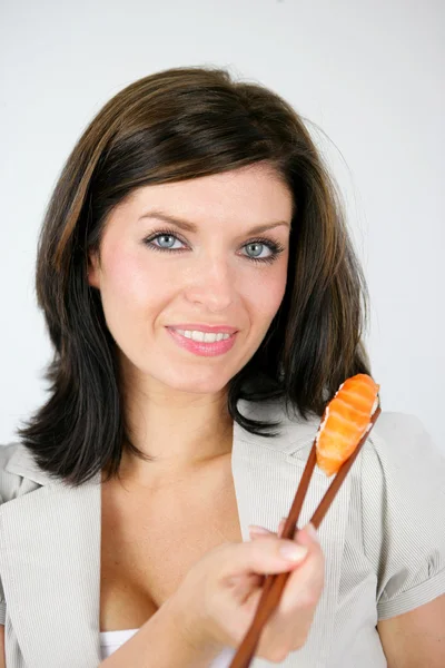 Žena jí kus sushi hůlkami — Stock fotografie