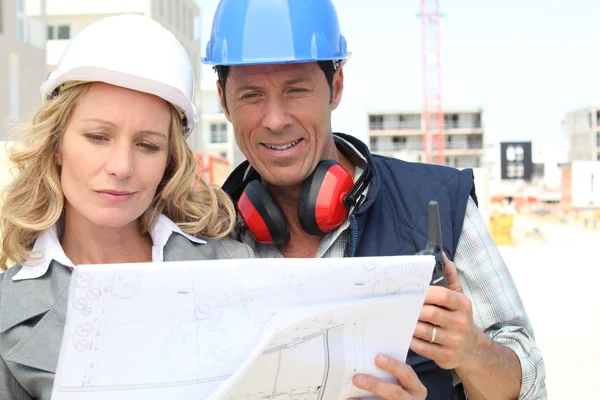 Trabalhador da construção civil a olhar para o desenho de um engenheiro — Fotografia de Stock