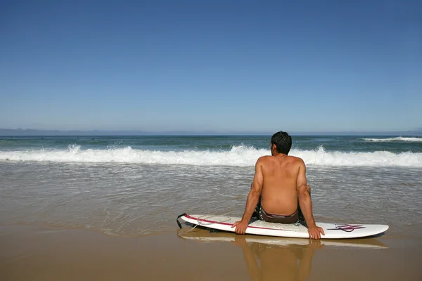 Człowiek siedział na deskę surfingową podziwiając widok — Zdjęcie stockowe