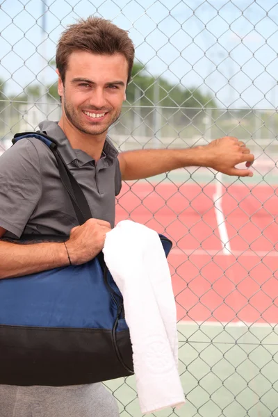 Jogador de tênis masculino sorridente com kitbag fora da quadra — Fotografia de Stock