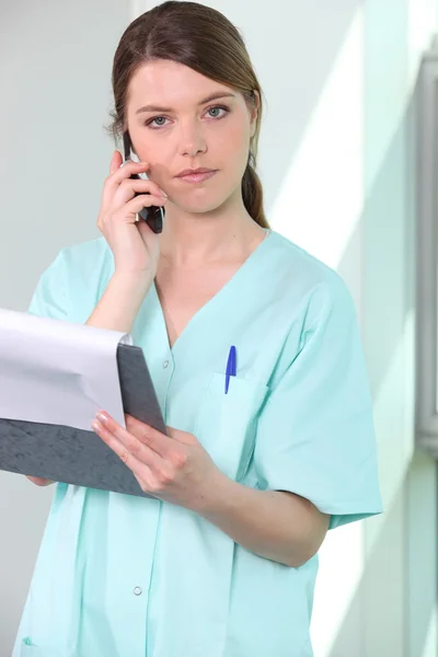 Enfermeira morena, carta de espera e telefone móvel — Fotografia de Stock