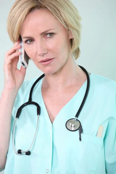 Медсестра на телефоне выглядит обеспокоенной — стоковое фото