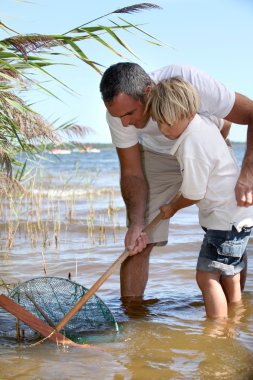 Father and son fishing together clipart