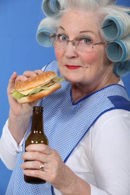 Old woman in rollers with a burger and a beer clipart