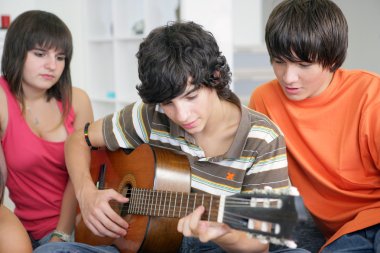 Teens listening to their peer play the guitar clipart