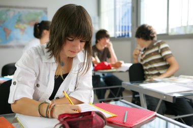 A teenage girl studying in a classroom clipart