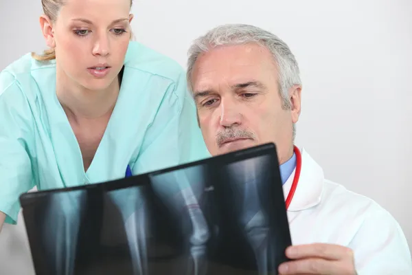 Médico y enfermera mirando una radiografía de piernas — Foto de Stock