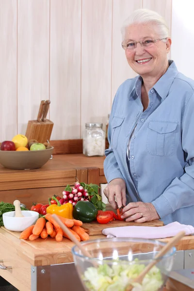 Old lady chopping vegetables — Stock Photo, Image
