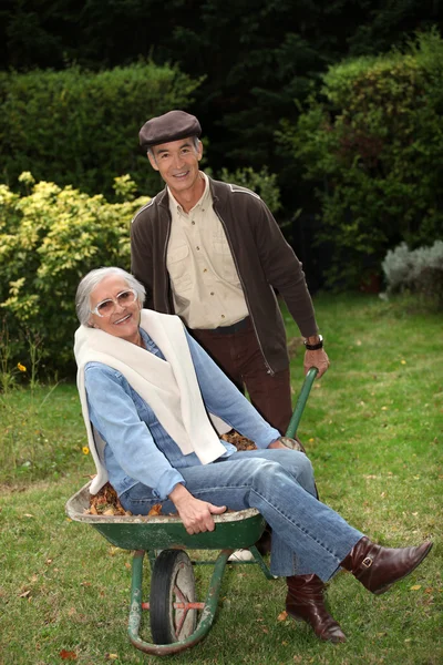 Older couple messing around with a wheelbarrow — Stock Photo, Image