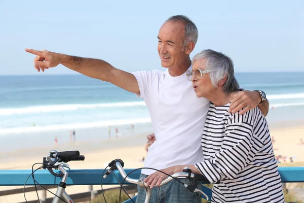 Senior koppel met fiets rijden op het strand — Stockfoto