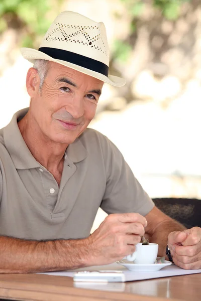 男子戴着帽子在露台上喝咖啡 — 图库照片