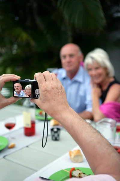 Senior taking a photograph of a couple — Stock Photo, Image