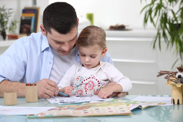 Young girl colouring with her father — Stok fotoğraf