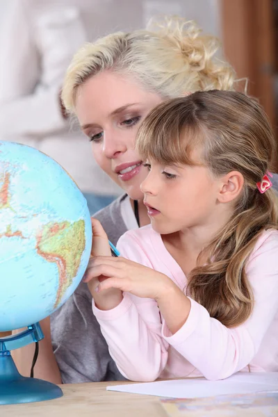 Moeder en dochter kijken naar een globe — Stockfoto