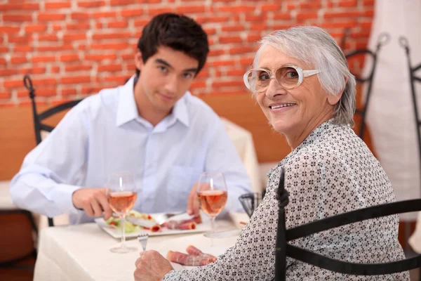 Young man and elderly woman in a restaurant — Stock Photo, Image