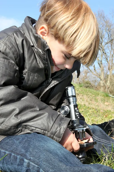 Мальчик с помощью микроскопа — стоковое фото