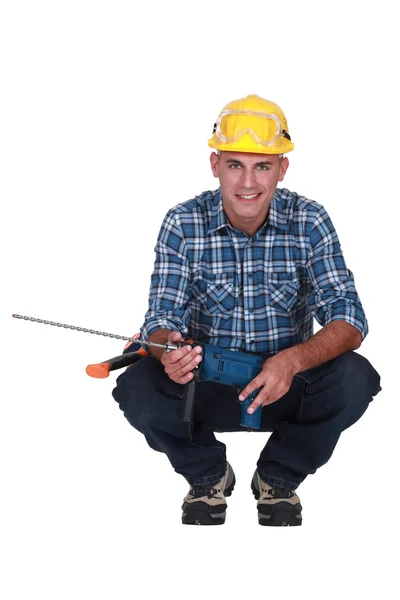 Man crouching with drill — Stock Photo, Image