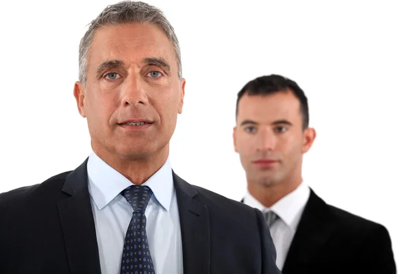Mature businessman in front of a young colleague — Stock Photo, Image