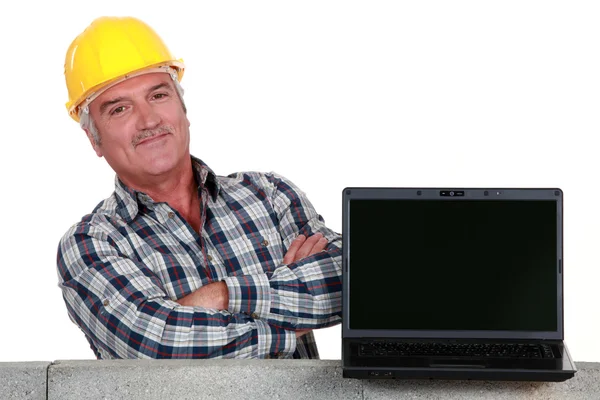 Orgulhoso pedreiro posando ao lado de seu laptop — Fotografia de Stock