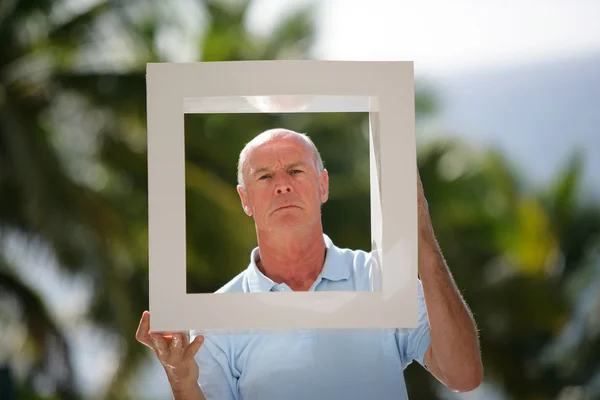Senior férfi feltartotta egy négyzet alakú keret — Stock Fotó