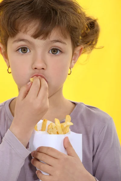 Молодая девушка ест картошку фри — стоковое фото