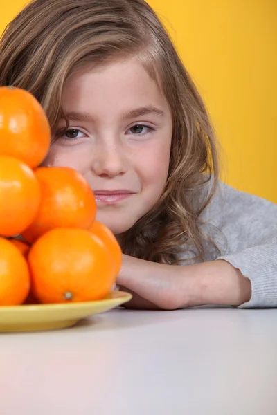 Mädchen versteckt sich hinter einem Teller Clementinen — Stockfoto