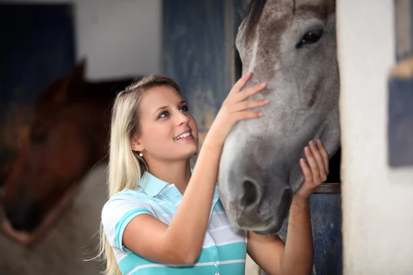Блондинка-подросток гладит лошадь — стоковое фото