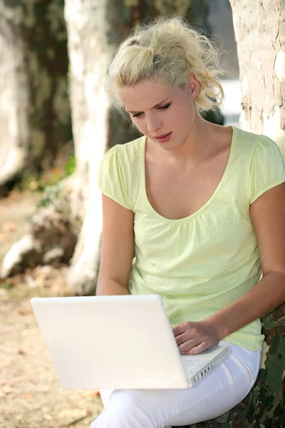 Kobieta za pomocą laptopa przez drzewa — Zdjęcie stockowe