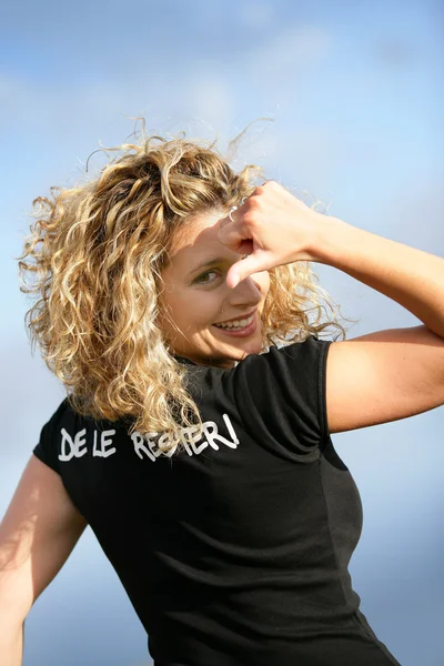 Жінка стояла на відкритому повітрі, вказуючи на логотип на спині футболки — стокове фото