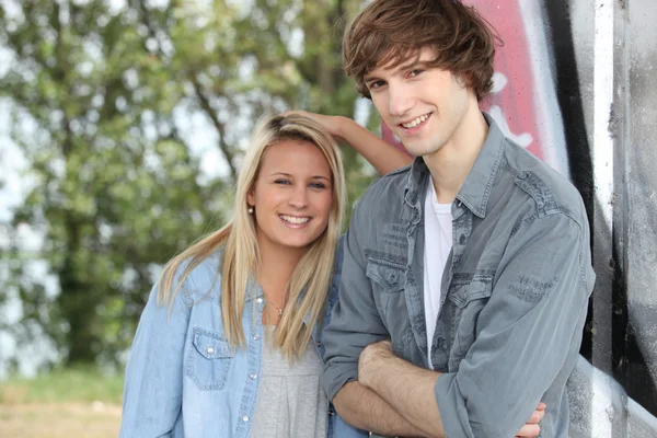 stock image Two teenagers stood outdoors leaning against wall