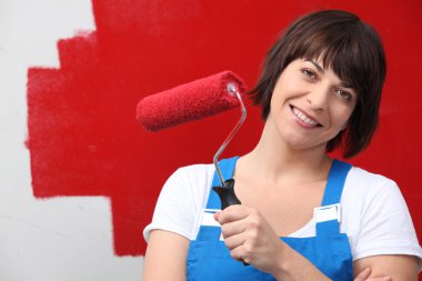 Woman painting wall red with roller clipart