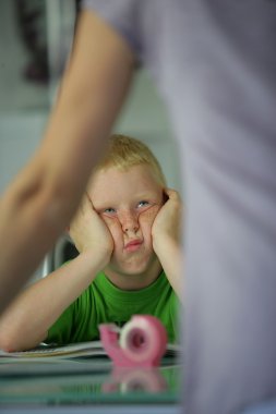 Little boy in the classroom looking bored clipart