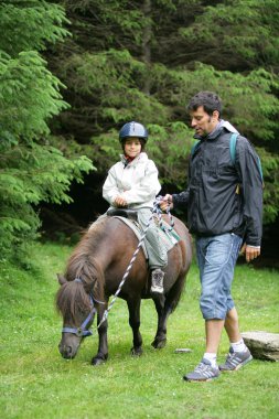 Father helping his daughter ride a pony clipart