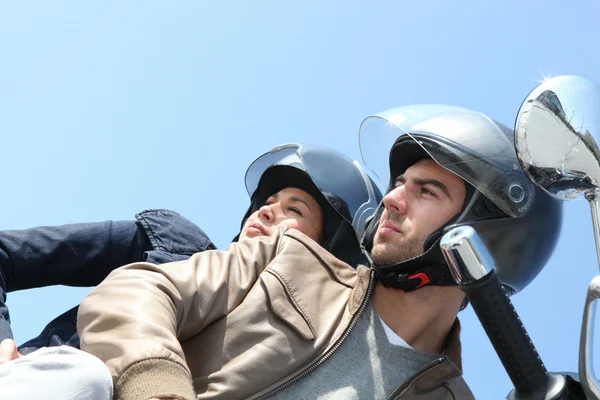 Una coppia su uno scooter guardando indietro — Foto Stock