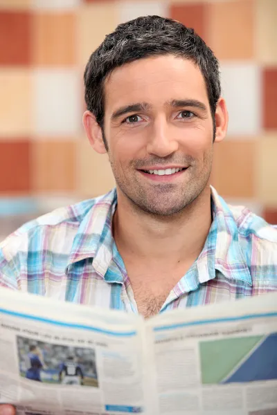 Un homme souriant lisant un journal — Photo