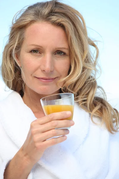 Женщина пьет апельсиновый сок — стоковое фото