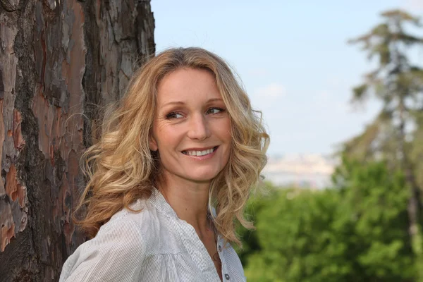 Woman leaning on a tree — Stock Photo, Image