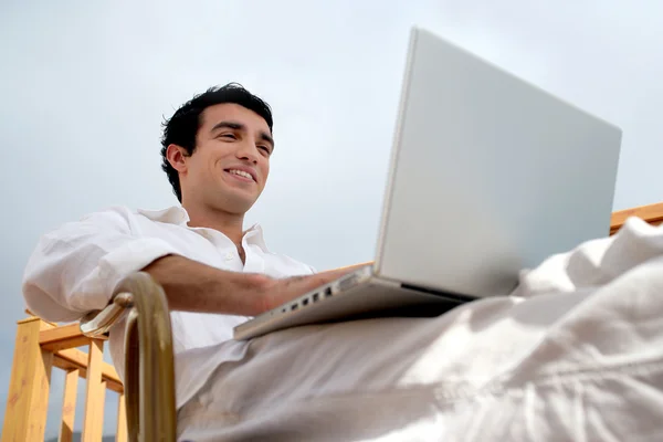 男子坐在花园椅子的笔记本电脑上 — 图库照片