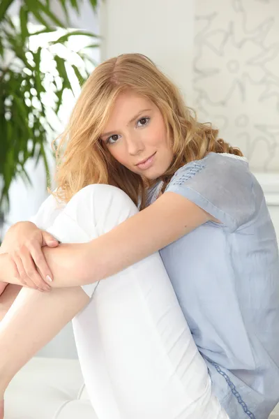 Ung blond kvinna sitter på sin säng — Stockfoto