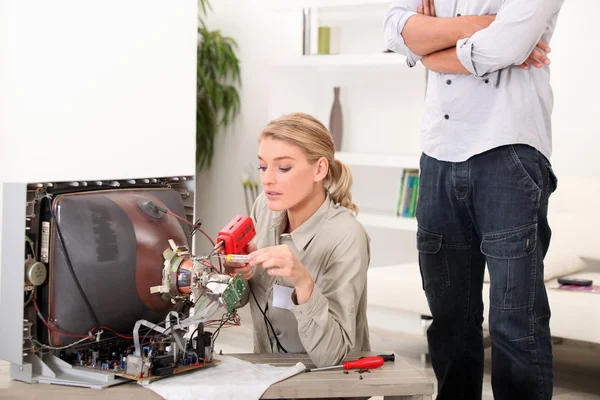 Eine Technikerin repariert einen Fernseher — Stockfoto