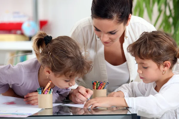 Young woman and little girls making coloring Stock Picture