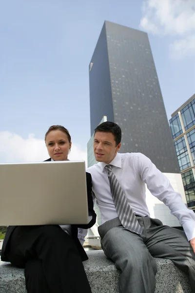 Jonge businesscouple zat met laptop in centrum van de stad — Stockfoto